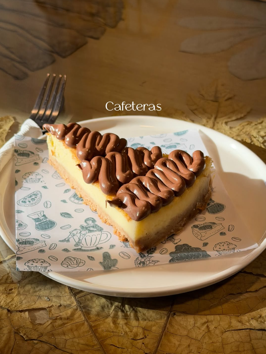 Porción de cheesecake con cobertura de chocolate de Cafeteras